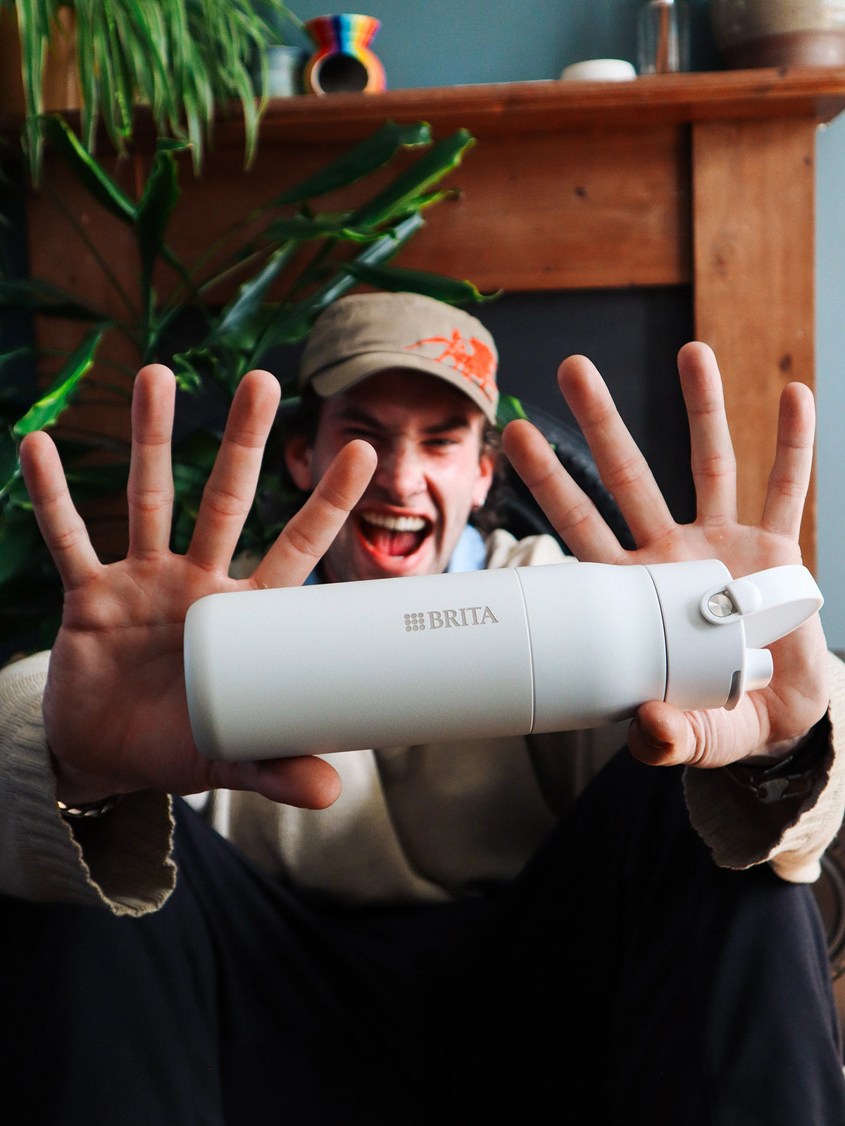 Person presenting a white BRITA LARQ Filter Bottle in a living room setting.
