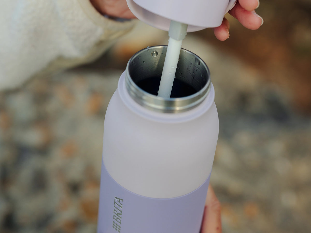 A close-up of a person pouring water into the florence by mills x BRITA LARQ bottle.
