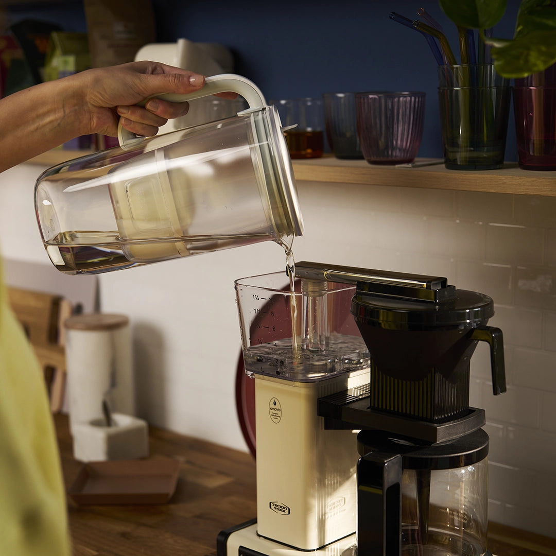 Pouring water with BRITA glass jug in grey in a coffee maker.
