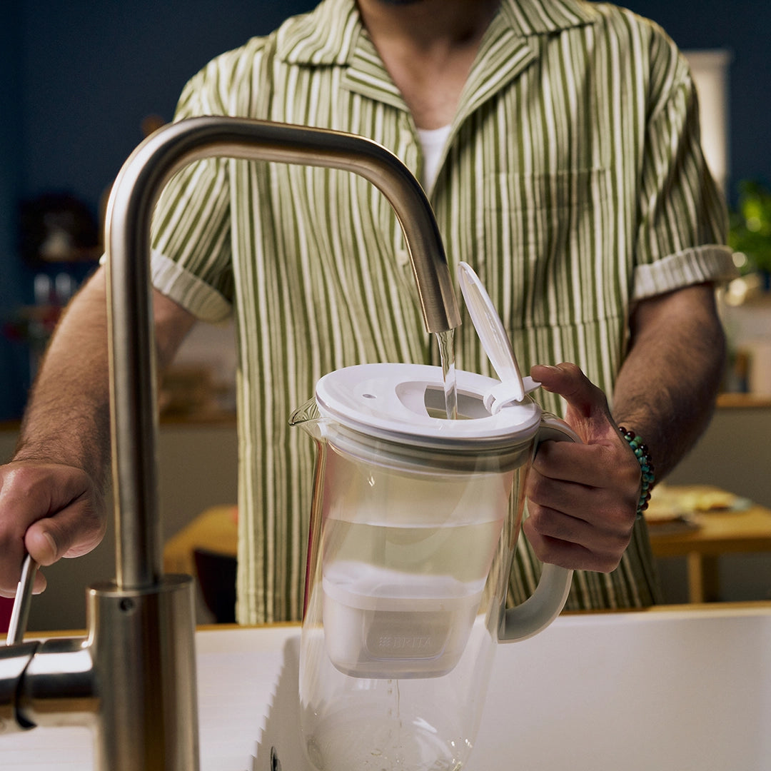 Man filling water in grey BRITA glass jug.
