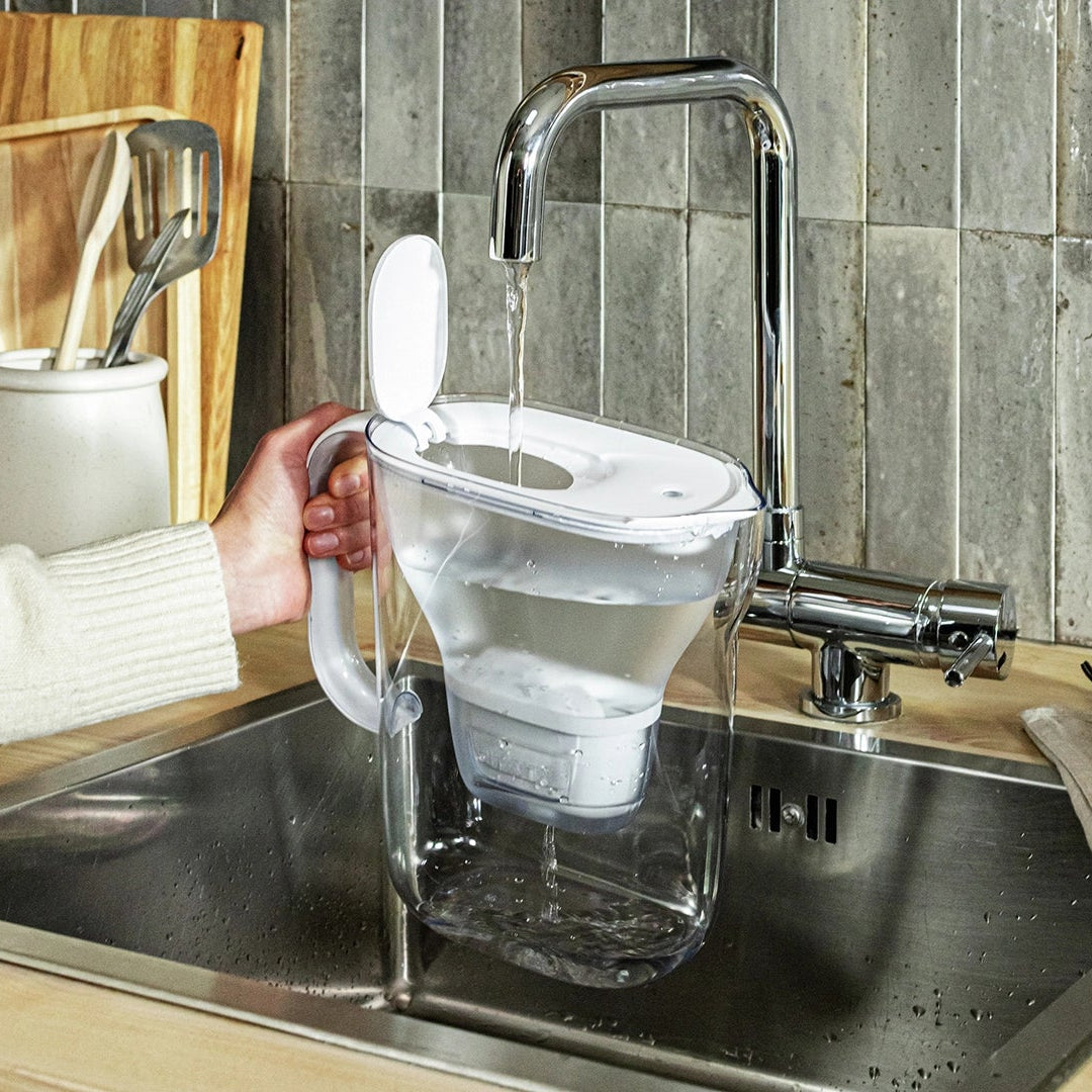 BRITA bianca Style Essential che viene riempita con acqua del rubinetto sotto un rubinetto della cucina.